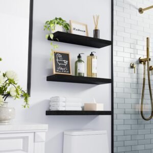 black floating shelves mounted in bathroom with plant and towels