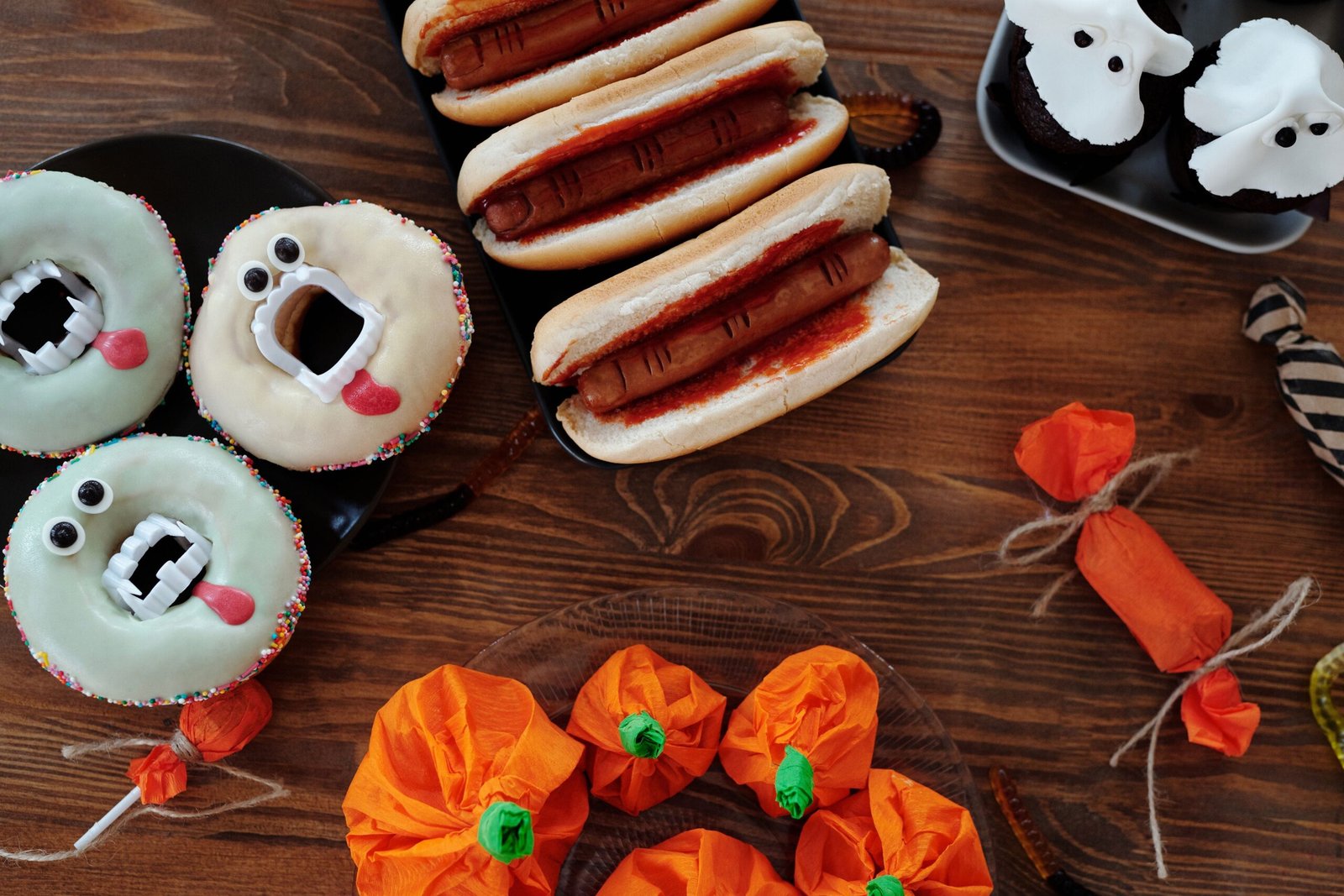 Halloween Food Safety: The Real 2-Hour Rule Most Hosts Ignore 1 Halloween party food spread with hot dogs donuts and cupcakes on serving trays